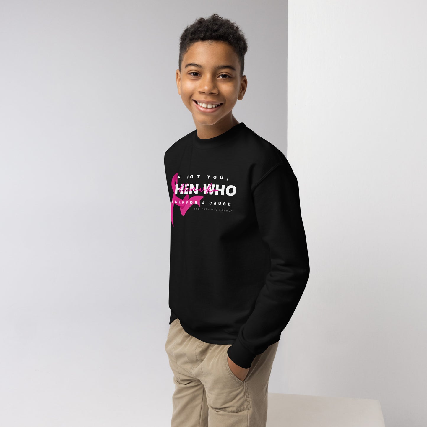 Young boy wearing a black sweatshirt with pink and white text on a plain background